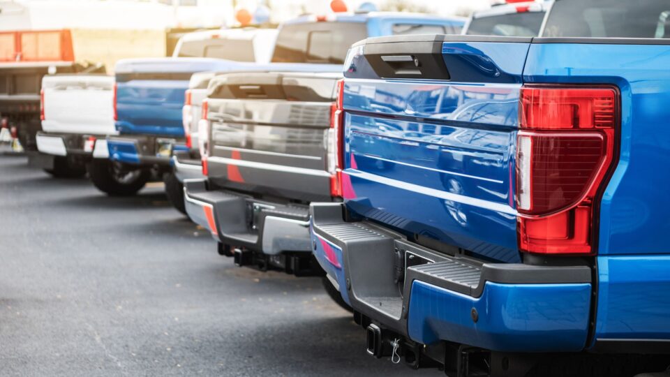 back of pickup trucks filling a parking lot
